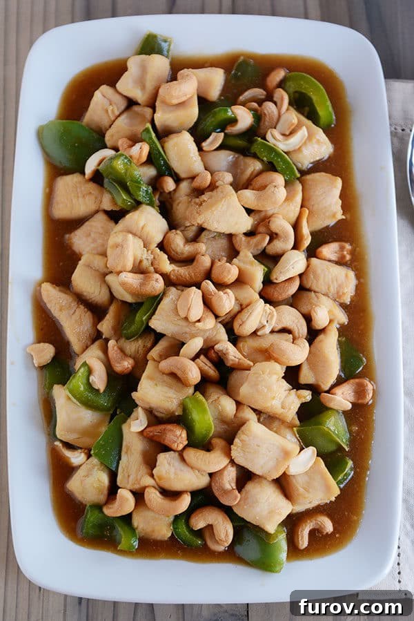 Quick Weeknight Chinese Cashew Chicken 2 Top down view of a large white platter of chinese cashew chicken with sauce and green peppers.