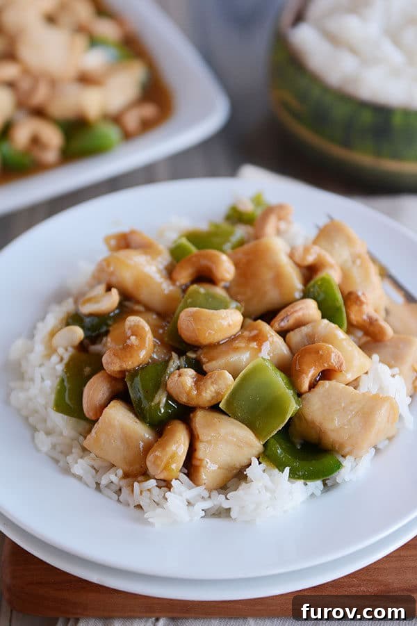 Quick Weeknight Chinese Cashew Chicken 3 A large serving of white rice topped with saucy cashew chinese chicken with green peppers.