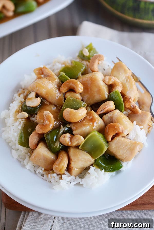 Quick Weeknight Chinese Cashew Chicken 5 Top view of a white plate of cooked rice topped with cashew chinese chicken.