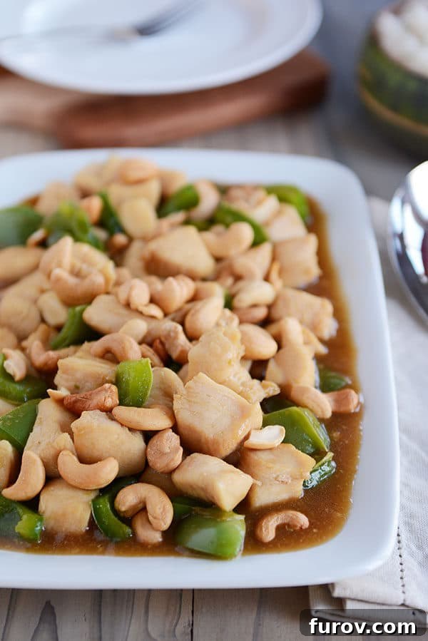 Quick Weeknight Chinese Cashew Chicken 6 A white platter of saucy cashew chicken with large green pepper chunks mixed in.
