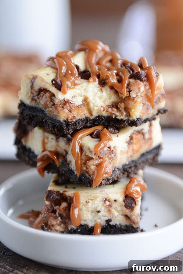 Perfectly cut Caramel Snickers cheesecake bars stacked invitingly on top of each other in a small white ramekin, highlighting their appealing geometry and rich color.