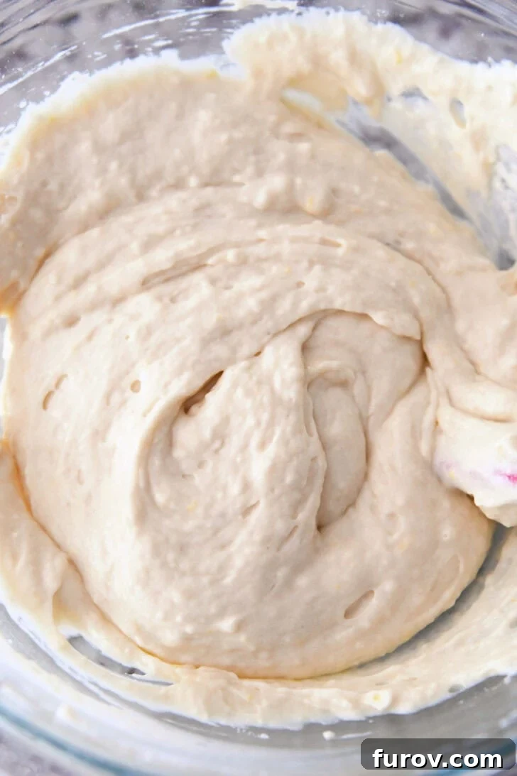 Top down view of lemon muffin batter in a glass bowl.