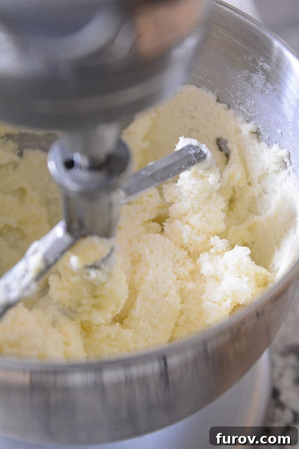 Creamed butter and sugar elegantly mixing inside a gleaming KitchenAid stand mixer bowl, ready for the next baking step.