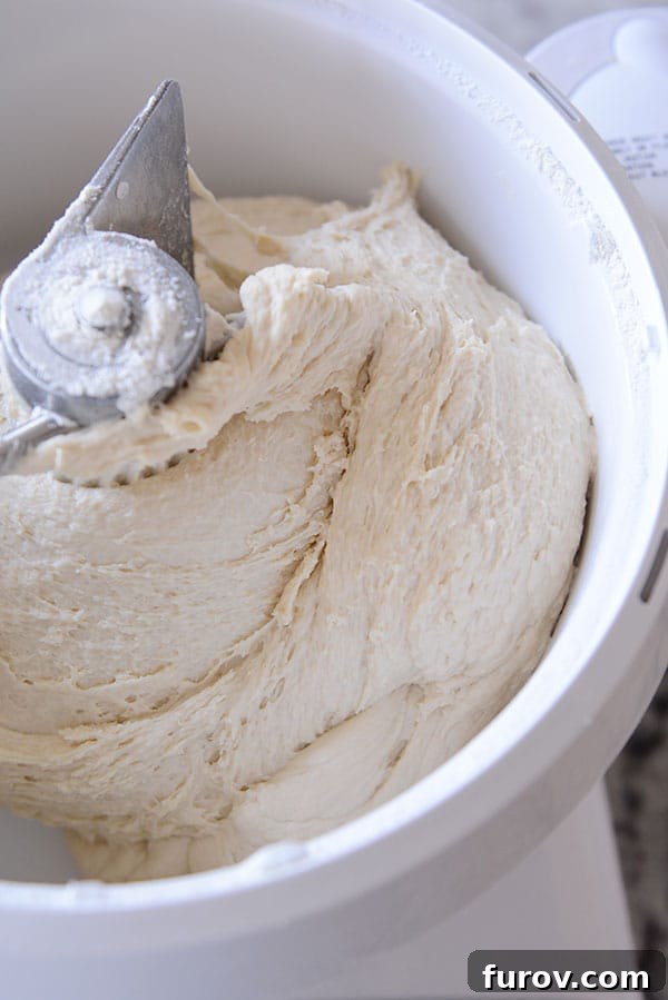 Close-up view inside a Bosch Universal mixer bowl, showing active bread dough being thoroughly mixed by the central dough hook.