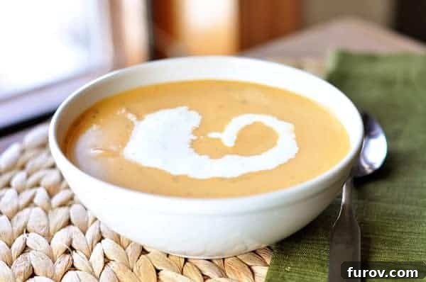 A beautifully presented bowl of creamy tomato bisque soup, garnished with a swirl of fresh cream and a sprig of basil.