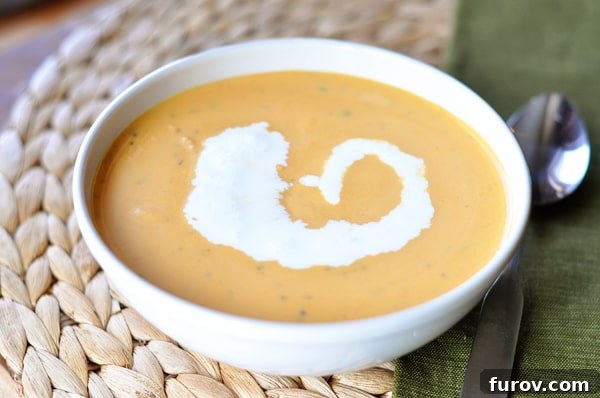 Close-up of creamy tomato soup in a white bowl, with an elegant swirl of cream in the center, ready to be enjoyed.