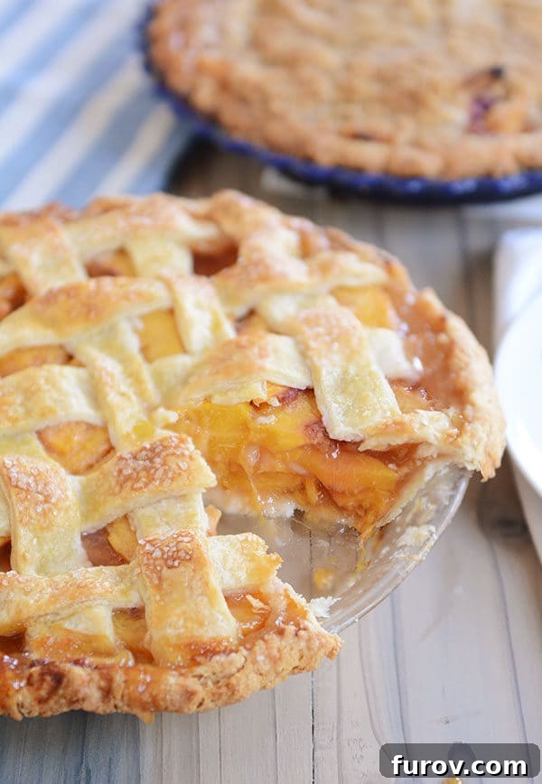 Juicy Fresh Peach Pie with Lattice or Crumb Topping 4 A freshly baked lattice-topped peach pie with a single slice removed, revealing the vibrant peach filling.