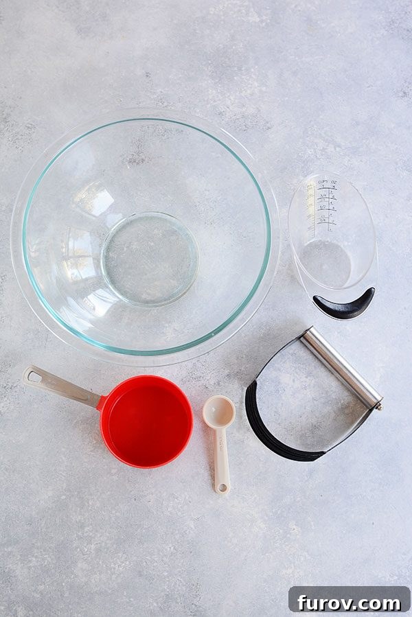 Kickstart Your Pie Making: Essential Tools and Ingredients 3 Top view of a glass bowl, a red dry measuring cup, a small spoon, and a liquid measuring cup, all essential for baking.