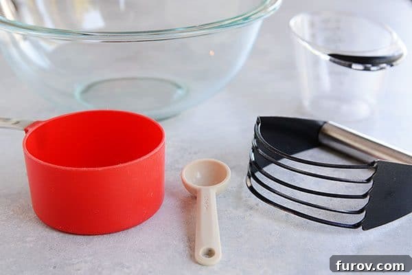 Kickstart Your Pie Making: Essential Tools and Ingredients 4 A glass bowl, red dry measuring cup, teaspoon, pastry blender, and liquid measuring cup, illustrating basic pie crust tools.
