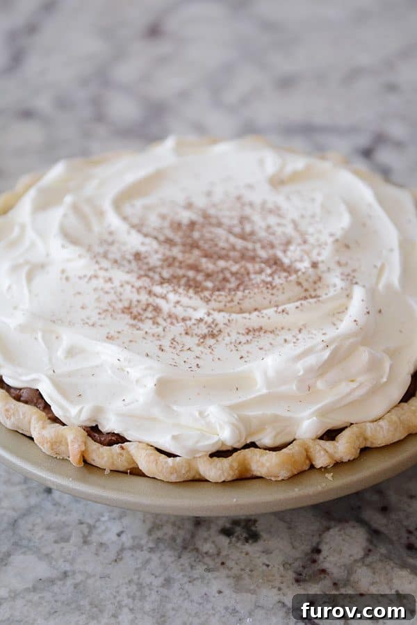 A chocolate ganache pie topped with whipped cream and dusted cocoa powder.