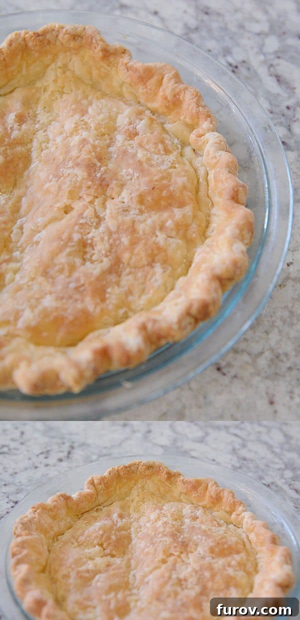 A golden brown cooked pie crust in a glass pie dish.