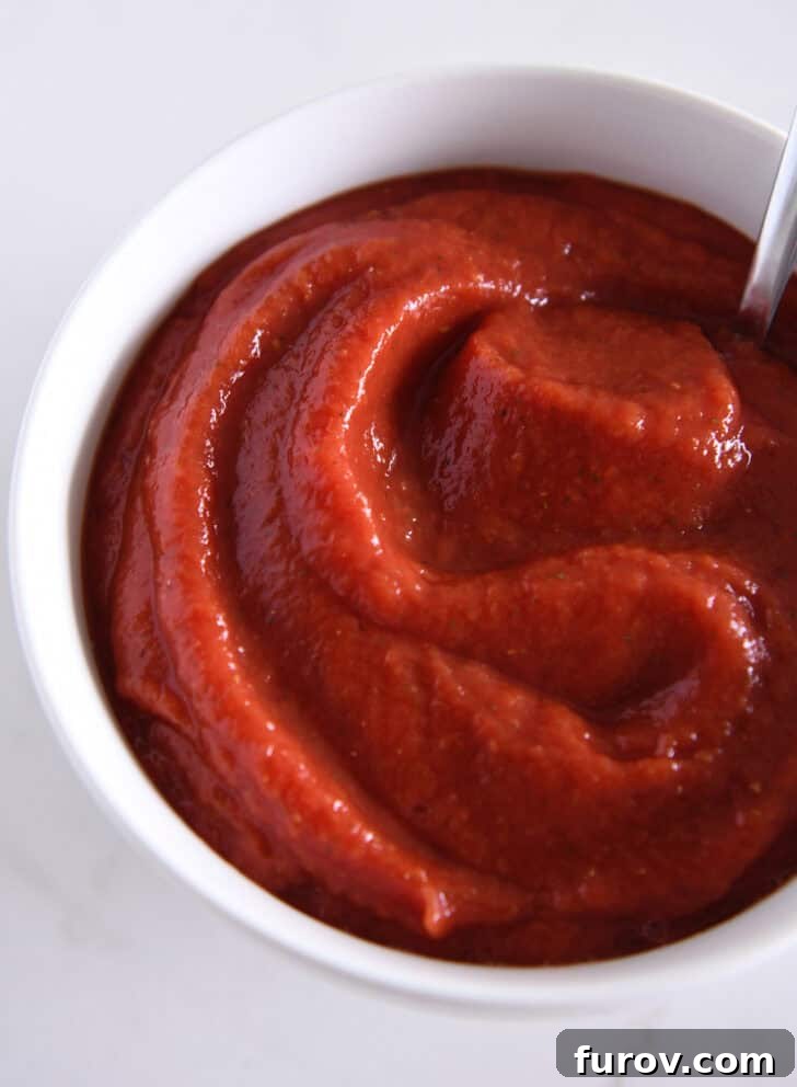 Top down view of a white bowl full of pizza sauce.