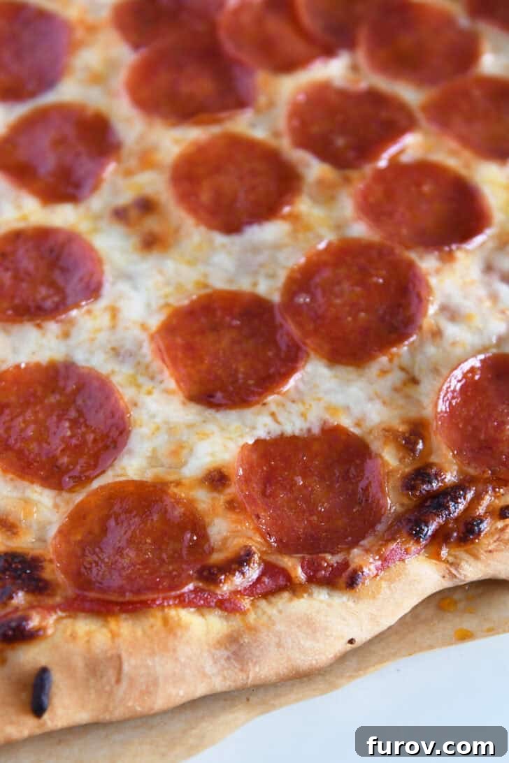 Baked pepperoni pizza on parchment paper.
