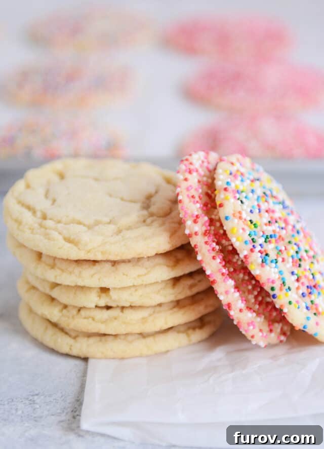 Effortless Soft and Chewy Drop Sugar Cookies 9 A stack of five perfectly baked soft and chewy sugar cookies on parchment paper.