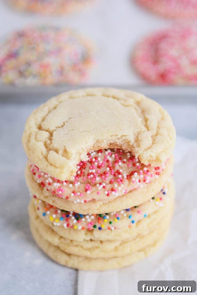 Effortless Soft and Chewy Drop Sugar Cookies 7 A delicious soft and chewy sugar cookie with a bite taken out, stacked on top of other cookies.