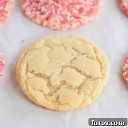 Baked sugar cookie on sheet pan next to cookies with sprinkles.