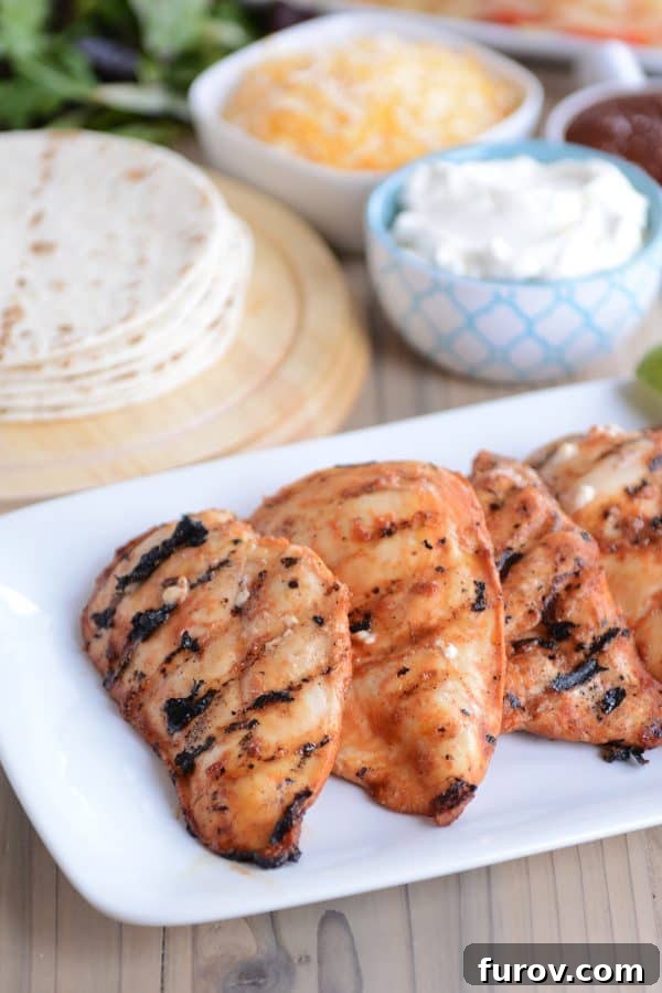 Three succulent pieces of grilled chipotle chicken resting on a pristine white platter, showcasing the beautiful char marks and rich color of the chicken.