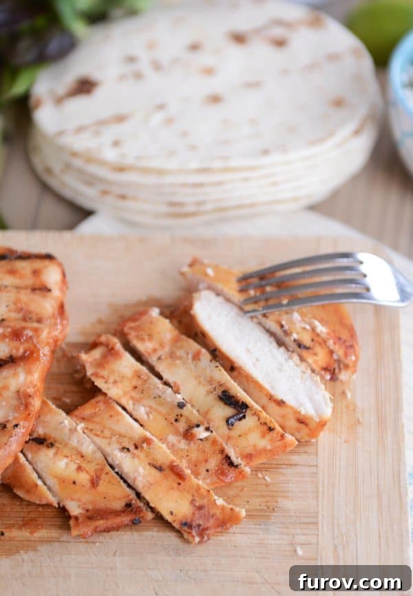 Perfectly grilled chipotle chicken, sliced into tender pieces and arranged on a rustic wooden cutting board, ready for serving.