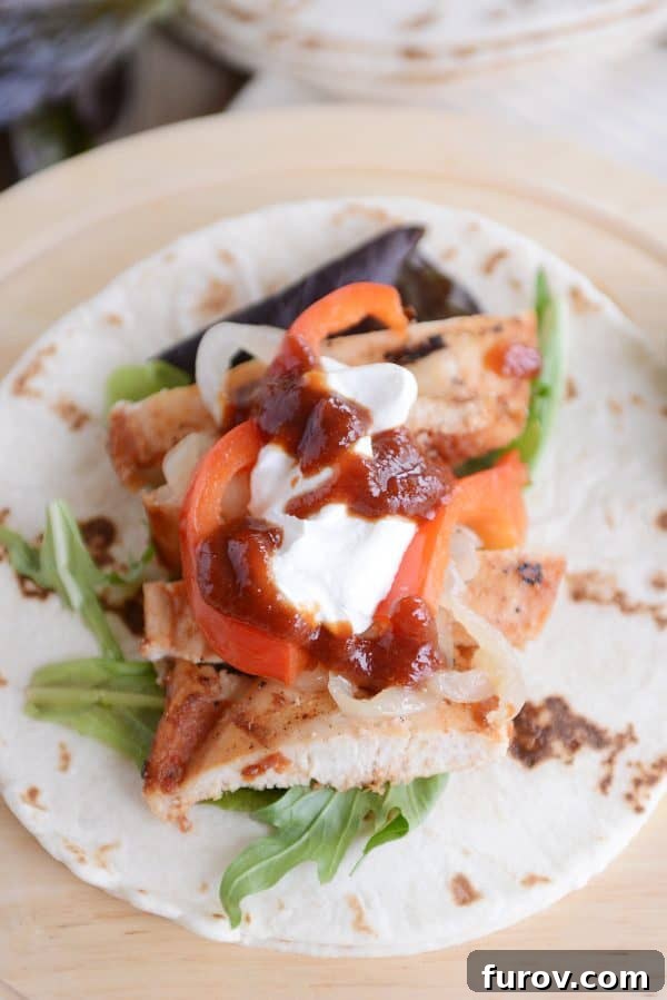 A delicious grilled chipotle chicken wrap, perfectly layered with tender chicken, caramelized grilled onions, and a swirl of cool sour cream on a warm tortilla.