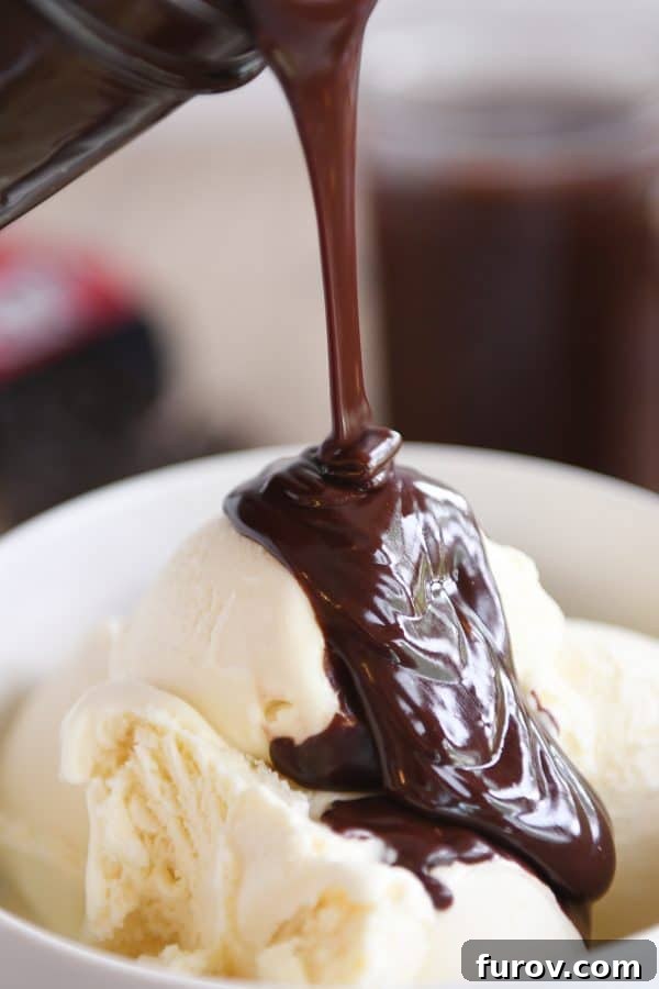 Vanilla ice cream in white bowl with 5-minute hot fudge sauce being poured on top, highlighting its smooth, rich texture.