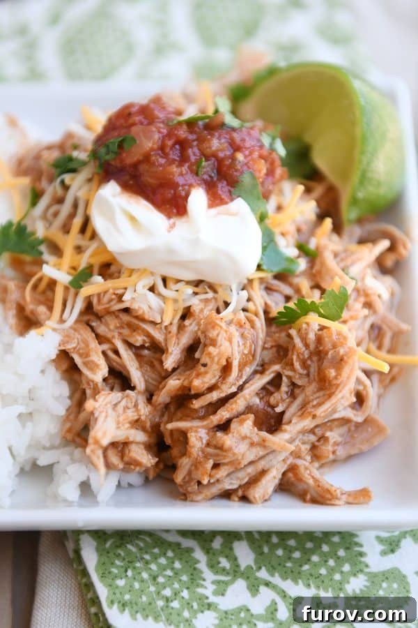 Instant pot Mexican pork on white tray with rice and beans and sour cream, salsa, and fresh limes.