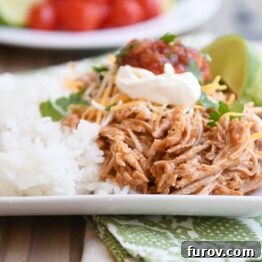 Instant pot Mexican pork on white tray with rice and beans and sour cream, salsa, and fresh limes.