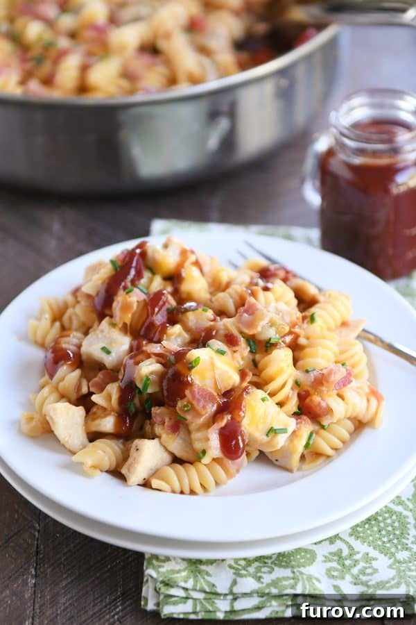 A close-up of Monterey BBQ chicken pasta on a white plate, garnished with fresh herbs.