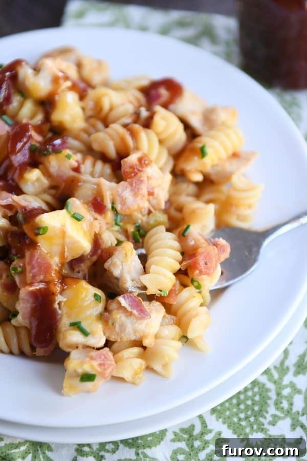 A close-up of Monterey BBQ chicken pasta on a white plate, highlighting the melted cheese.