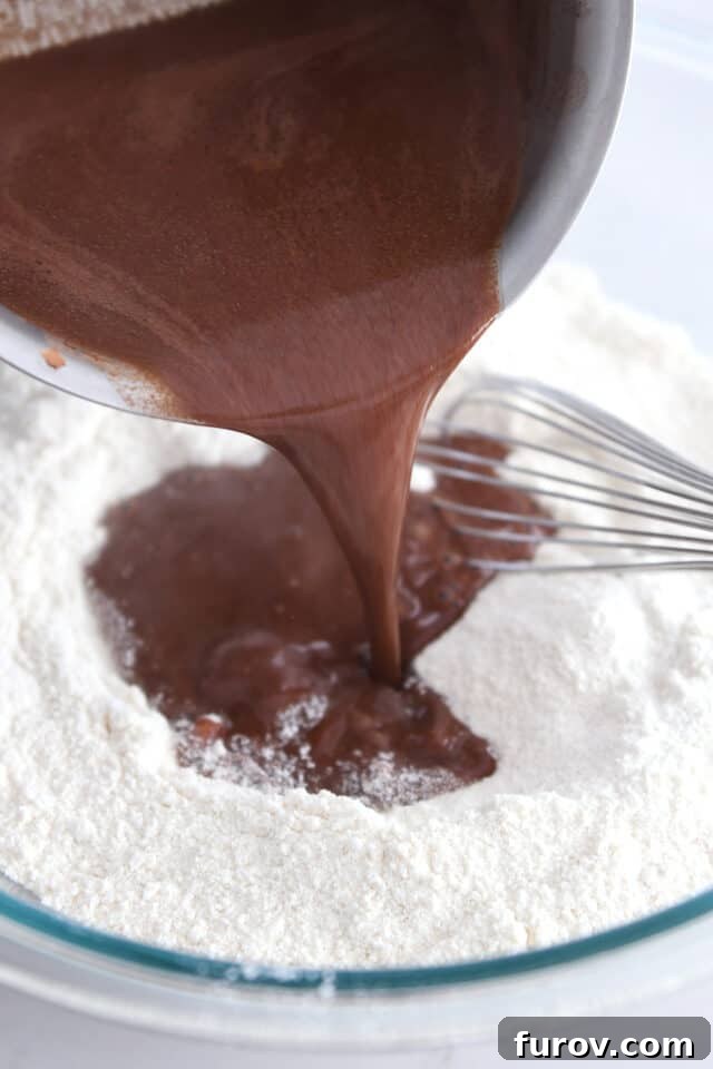 Pouring melted cocoa powder and butter over flour and salt. Combining wet and dry ingredients for the chocolate cake.