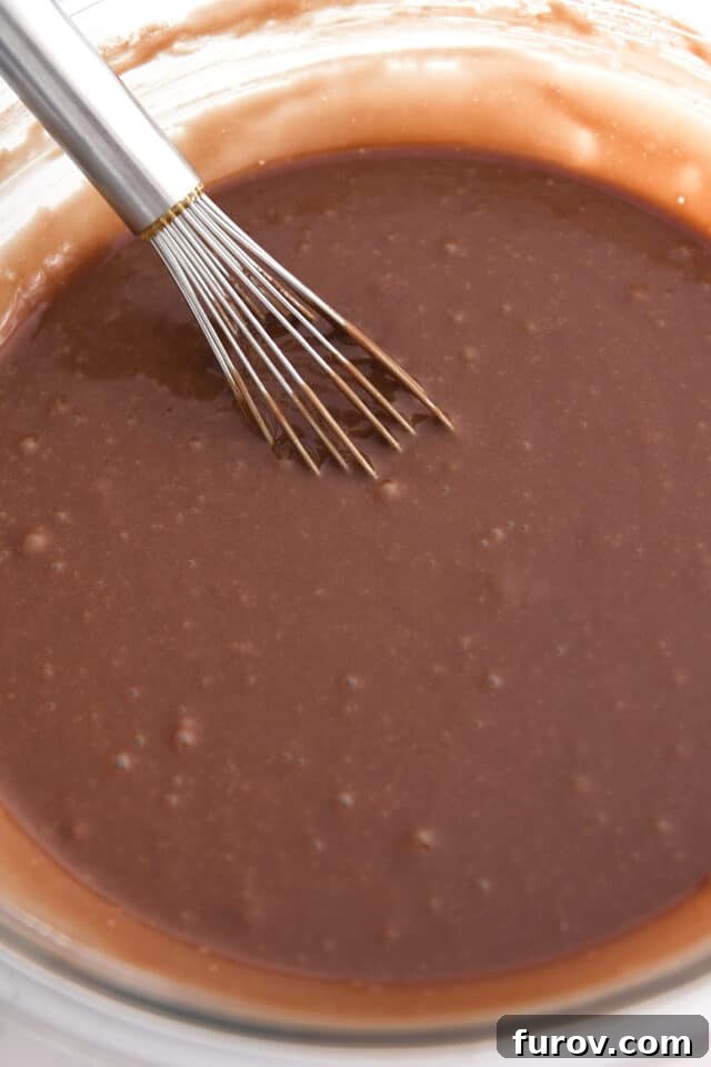 Whisking chocolate cake batter in glass bowl. The thin, bubbly consistency of a perfectly mixed Texas Sheet Cake batter.