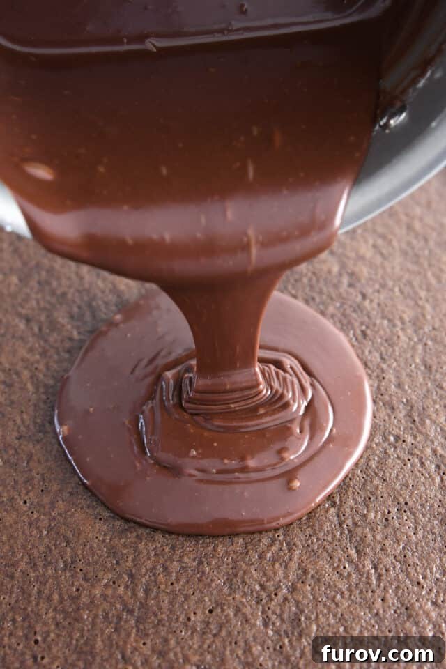 Pouring warm frosting over chocolate sheet cake. The essential step for a moist Texas Sheet Cake.