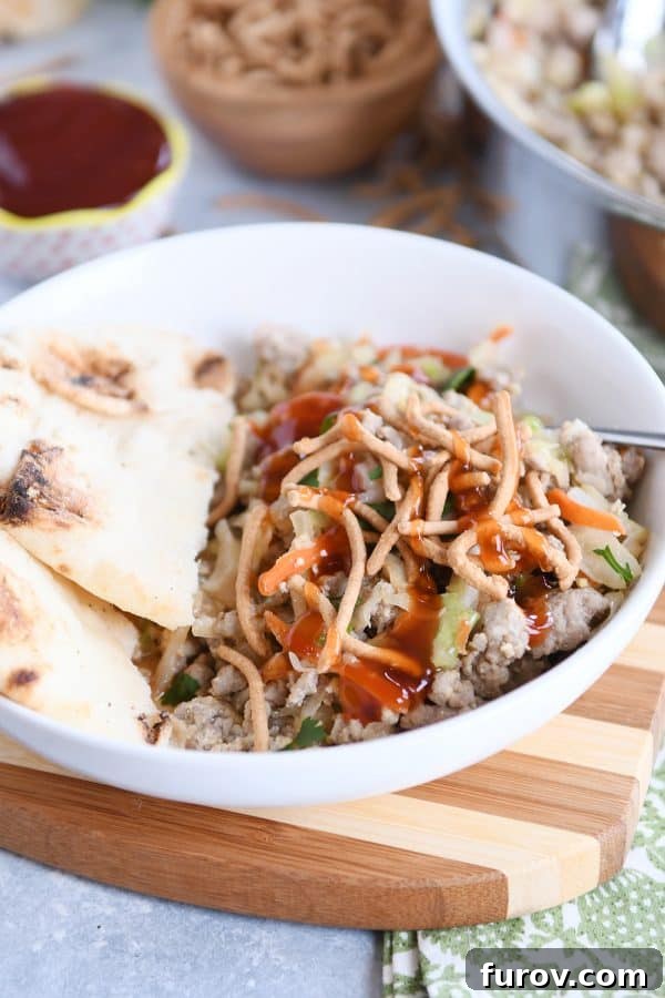 One-Pan Egg Roll Bowl 2 Ground turkey, cabbage, naan in white bowl drizzled with sweet and sour sauce.