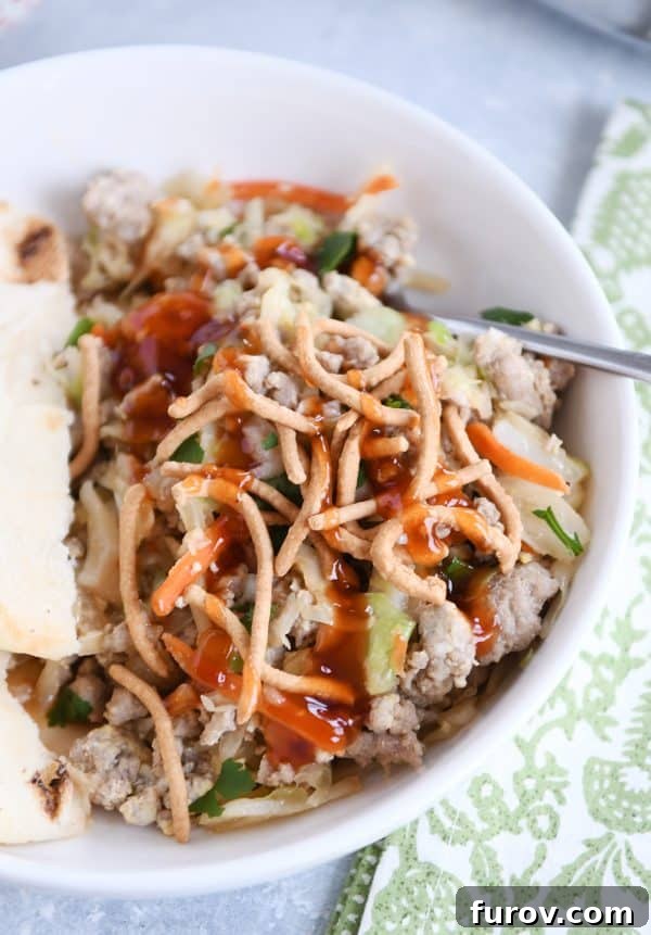 One-Pan Egg Roll Bowl 5 Ground turkey, cabbage, naan in white bowl drizzled with sweet and sour sauce.