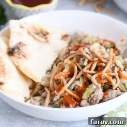 Ground turkey, cabbage, naan in white bowl drizzled with sweet and sour sauce.