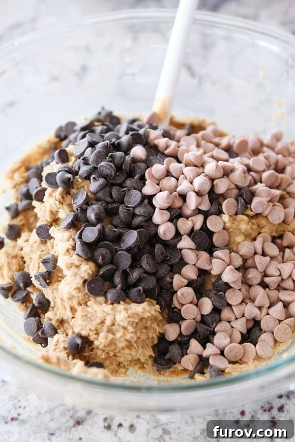 A large bowl filled with rich, creamy monster cookie dough, studded with chocolate chips and butterscotch chips, ready to be mixed to perfection.