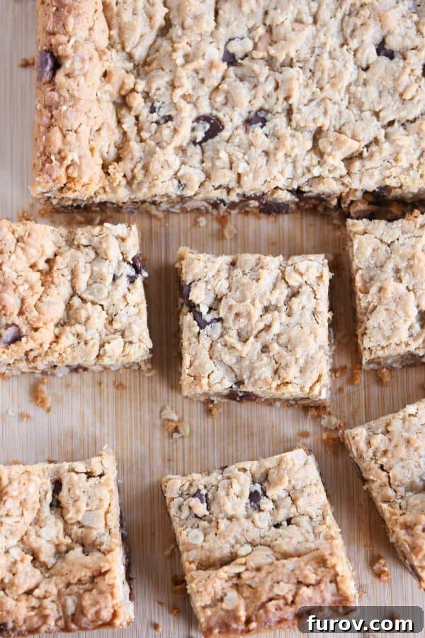 A top-down view of perfectly cut butterscotch peanut butter monster cookie bars arranged on a wooden board, showcasing their golden edges and soft centers.