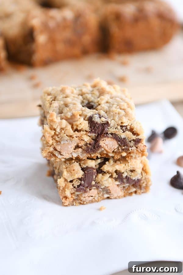 Two mouth-watering butterscotch peanut butter monster cookie bars stacked, highlighting their thick, chewy texture and visible chips.