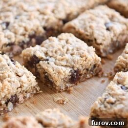 Slab of monster cookie bars cut into squares on wood board.