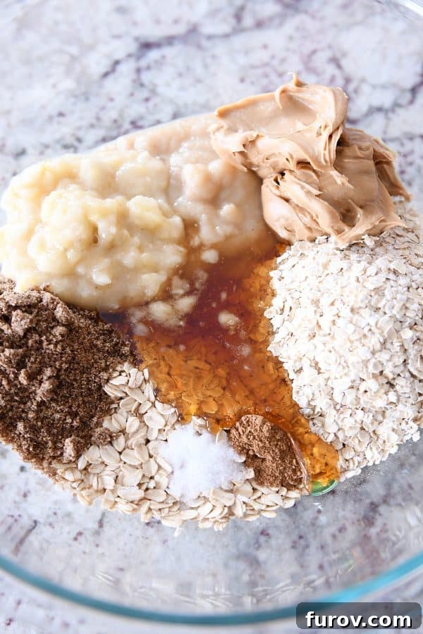 All the nutritious ingredients for healthy breakfast cookies laid out in glass bowls, including oats, peanut butter, bananas, and flaxseed meal.