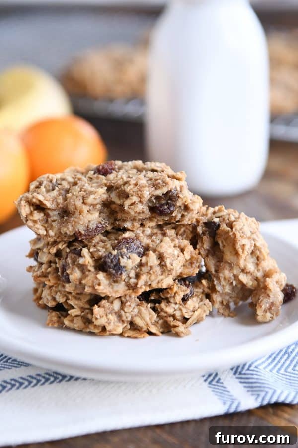 A baked oat breakfast cookie on a white plate, broken in half to reveal its soft, wholesome interior.