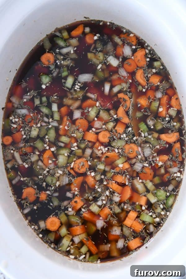 Top down view of beef broth added to slow cooker for beef noodle soup.