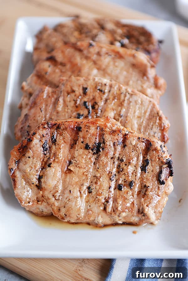 Mouthwatering Grilled Pork Chops 2 Four perfectly cooked, golden-brown grilled pork chops arranged neatly on a serving platter, garnished with fresh herbs, ready to be enjoyed.