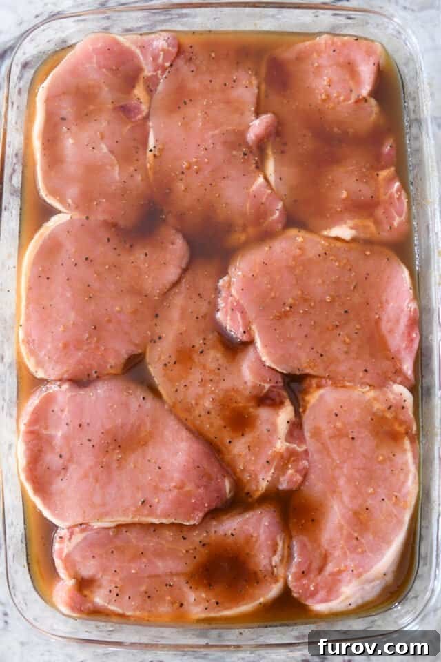 Mouthwatering Grilled Pork Chops 4 A clear glass baking dish filled with boneless pork chops, generously coated in the savory marinade, ready for refrigeration.