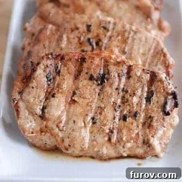 A close-up of a succulent grilled pork chop, showcasing its golden-brown crust and juicy interior, ready to be carved.