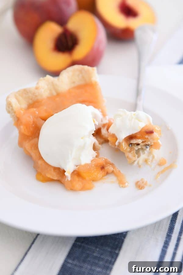 Bite of fresh peach pie on fork on white plate.