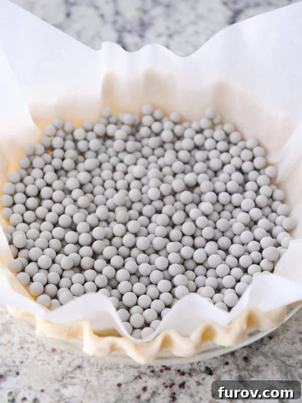 A pie crust covered with parchment and dry beans to get blind baked.