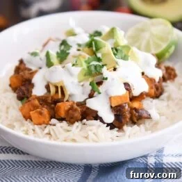 A deliciously arranged sweet potato black bean burrito bowl with white rice, fresh avocados, cilantro, and lime, ready to be enjoyed.