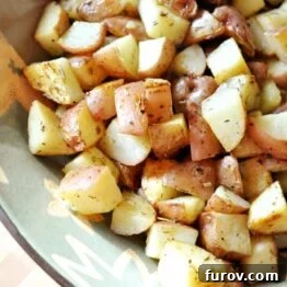 Close-up of herb-roasted potatoes in a small bowl, garnished with fresh herbs.