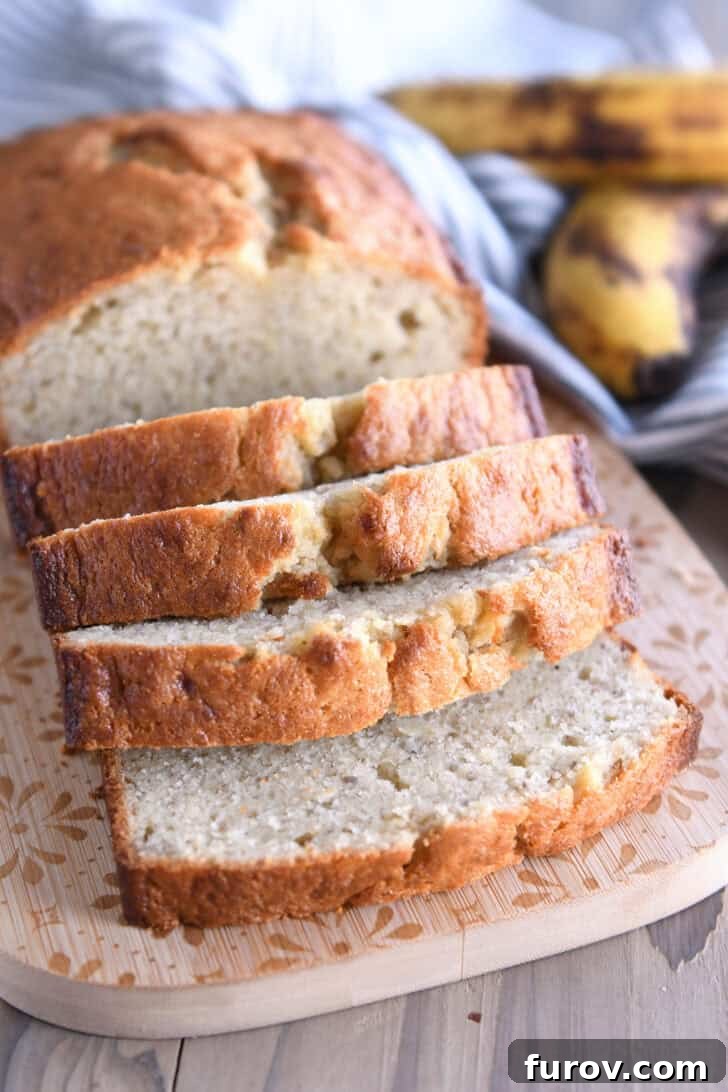 Four golden slices of buttermilk banana bread resting on a rustic wooden cutting board, highlighting its light, tender crumb.