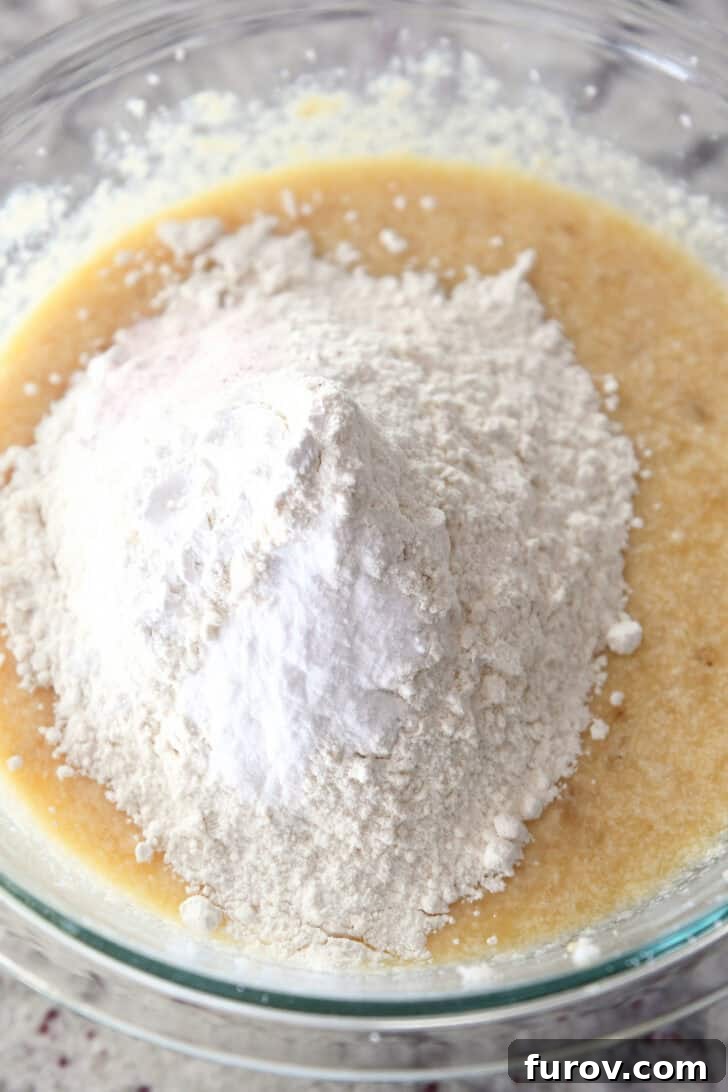 Close-up of all banana bread ingredients, including flour, in a glass bowl before mixing.